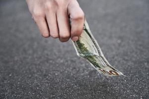 hand- plukken een honderd dollar bankbiljet van grond. gevonden geld concept foto