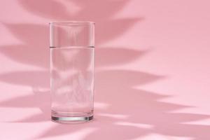 glas van water en blad schaduw Aan een roze achtergrond foto