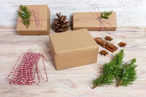 creatief hobby. geschenk inpakken. verpakking modern Kerstmis Cadeau dozen in elegant grijs papier met satijn rood lintje. top visie tafel met Spar boom takken, decoratie foto