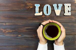 vrouw handen Holding kop van koffie en koekjes Aan houten tafel foto