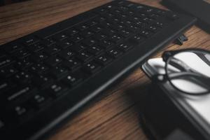 top visie van hout wijnoogst bureau gefocust Aan laptop met kladblok, smartphone en bril. werkplek. werk van huis. kantoor bureau. foto