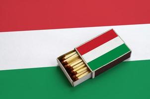 Hongarije vlag is getoond in een Open luciferdoosje, welke is gevulde met wedstrijden en leugens Aan een groot vlag foto
