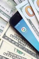 smartphone scherm met google app en veel van honderd dollar rekeningen. bedrijf en sociaal netwerken concept foto