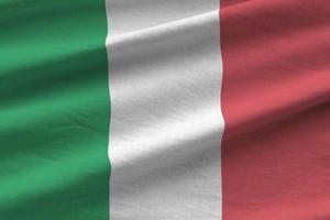 Italië vlag met groot vouwen golvend dichtbij omhoog onder de studio licht binnenshuis. de officieel symbolen en kleuren in banier foto