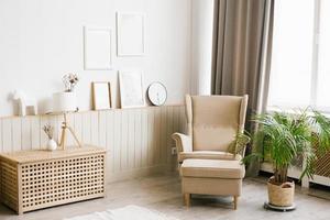 modern Scandinavisch leven kamer interieur in beige kleuren. fauteuil, palm boom in een pot, mockup kaders Aan de muur foto