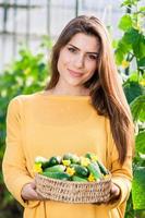 vrouwelijke broeikasgassen werknemer met een mand vol verse komkommers