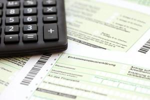 Duitse jaar- inkomen belasting terugkeer verklaring en rekenmachine leugens Aan accountant tafel dichtbij omhoog. de concept van belasting betalen periode in Duitsland foto