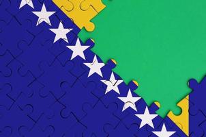 Bosnië en herzegovina vlag is afgebeeld Aan een voltooid decoupeerzaag puzzel met vrij groen kopiëren ruimte Aan de Rechtsaf kant foto
