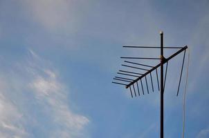 een oud en roestig televisie antenne tegen een bewolkt blauw lucht foto