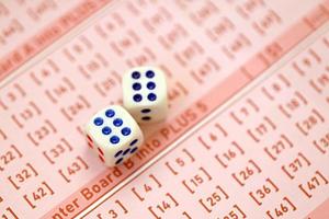 Dobbelsteen kubussen leugens Aan roze het gokken lakens met getallen voor markering naar Speel loterij. loterij spelen concept of het gokken verslaving. dichtbij omhoog foto