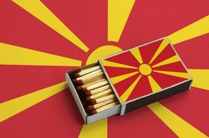 Macedonië vlag is getoond in een Open luciferdoosje, welke is gevulde met wedstrijden en leugens Aan een groot vlag foto