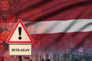 Letland vlag en coronavirus 2019-ncov alarm teken. concept van hoog waarschijnlijkheid van roman coronavirus het uitbreken door op reis toeristen foto