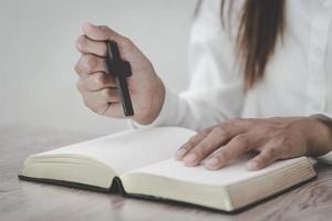 de vrouw houdt het kruis vast en bidt met haar Schriften op tafel. foto