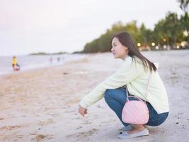 Aziatisch Dames op reis naar de zee zittend Aan de strand op zoek in de omgeving van. vrij monster vrijlating kom tot rust in de atmosfeer Daar is een achtergrondverlichting bokeh. foto