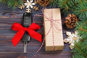 auto sleutel met kleurrijk boog met geschenk doos en Kerstmis decoratie Aan houten achtergrond foto