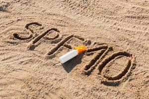 zon beschermen factor tien. spf 10 woord geschreven Aan de zand en wit fles met zonnebrand room. huid zorg concept achtergrond foto