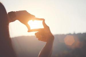 planning en visie concept van nieuw jaar begin, vrouw hand- maken kader gebaar vind focus Bij zonsondergang, vrouw op zoek voor perspectief naar vastleggen de betekenis van een Doorzichtig aanstaande doelwit. foto