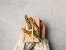 vrouw handen Holding Kerstmis geschenk doos in grijs beton achtergrond foto