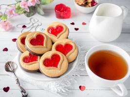 eigengemaakt koekjes met een rood jam hart Valentijnsdag dag kop van thee foto