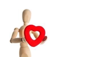 de houten figuur van een Mens houdt in zijn handen een rood hart Aan een wit achtergrond. geeft de hart foto