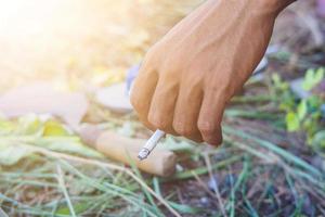 een hand- een Mens Holding een sigaret wazig sikkel achtergrond en slippers foto