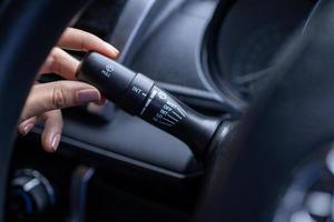 vinger is spinnen een wisser controle knop Aan de auto stuurinrichting wiel, detailopname en zachte focus visie. foto