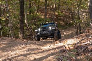 heet veren, aar, Verenigde Staten van Amerika, 2022 - een frontaal visie van een zwart jeep Rubicon schalen een heuvel Aan een Woud pad. foto