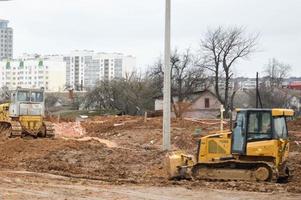 veel krachtig industrieel zwaar gespecialiseerd bouw uitrusting van trekker graafmachines en bulldozers maken weg reparaties gedurende de bouw van een nieuw micro-district in een groot stad foto