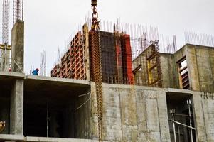 werken mannetje Bouwers zijn werken Aan de dak van een groot monolithisch kader huis, gebouw, en nieuw gebouw onder bouw. bouw van de gebouw in de nieuw micro wijk van de groot stad foto