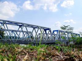 spoorweg brug, onder de groot bruin rivier, Doorzichtig blauw lucht foto