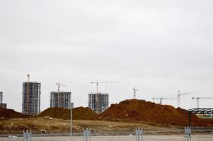 bouw van een nieuw microdistrict met hoog huizen, nieuw gebouwen met ontwikkelde infrastructuur met de helpen van groot industrieel kranen en professioneel bouw uitrusting in een groot stad foto