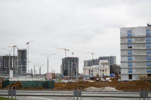 bouw van een nieuw microdistrict met hoog huizen, nieuw gebouwen met ontwikkelde infrastructuur met de helpen van groot industrieel kranen en professioneel bouw uitrusting in een groot stad foto