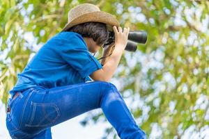 dichtbij omhoog vrouw slijtage hoed en houden verrekijker in gras veld- foto