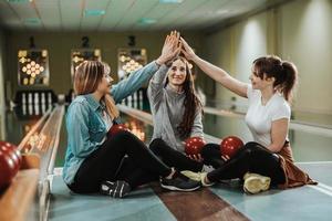 drie vrouw vrienden hebben pret en vieren in een bowling steeg foto