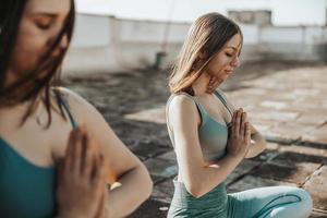 twee vrouw aan het doen yoga buitenshuis Aan een op het dak terras foto