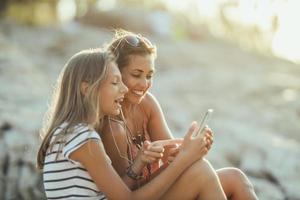 twee vrouw vrienden hebben pret terwijl genieten van een zomer vakantie Bij de strand foto