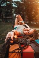 vrouw met lang afro vlechtjes hebben pret Aan de bank in de park foto