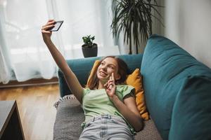 tiener meisje gebruik makend van slim telefoon terwijl hebben vrije tijd tijd Bij haar huis foto