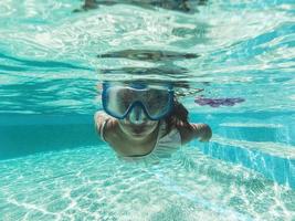 weinig meisje zwemmen onderwater- in zwembad foto