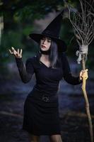 portret van mooi Aziatisch sexy vrouw slijtage zwart heks kostuum met bezem, halloween festival concept foto