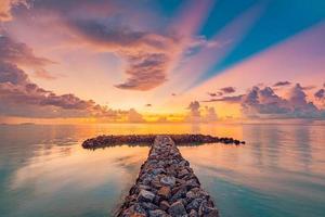 verbazingwekkend zomer zonsondergang met Golf breker. stenen rotsen onder verbazingwekkend zonsondergang kleuren, lucht wolken met water reflecties. ontspannende rustig zonlicht. schoonheid reizen zeegezicht landschap, middellandse Zee strand foto