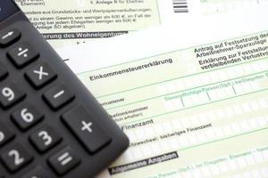 Duitse jaar- inkomen belasting terugkeer verklaring en rekenmachine leugens Aan accountant tafel dichtbij omhoog. de concept van belasting betalen periode in Duitsland foto