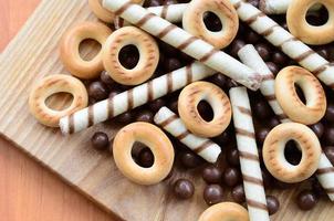 krokant buisjes, chocola smelten ballen en bagels liggen Aan een houten oppervlak. mengen van divers snoepgoed foto