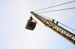 oud geel mechanisch clamshell grijp Aan blauw lucht achtergrond foto