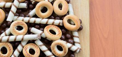 krokant buisjes, chocola smelten ballen en bagels liggen Aan een houten oppervlak. mengen van divers snoepgoed foto