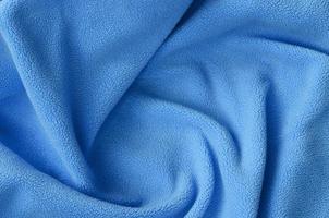 de deken van harig blauw fleece kleding stof. een achtergrond van licht blauw zacht pluche fleece materiaal met een veel van Verlichting vouwen foto