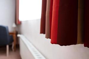 rood gordijnen hangen Aan de venster, in de hotel kamer, in een knus interieur. foto