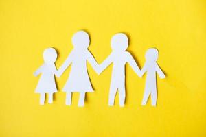gelukkig papier besnoeiing familie Holding handen Aan geel achtergrond foto