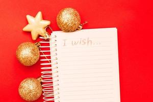 goud Kerstmis ballen en speelgoed met leeg blanco Notitie vel Aan een rood achtergrond foto