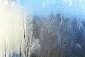bevroren winter venster met glimmend ijs vorst patroon structuur foto